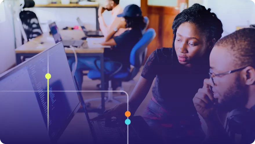 Two developers collaborating at a computer screen in a colorful modern office