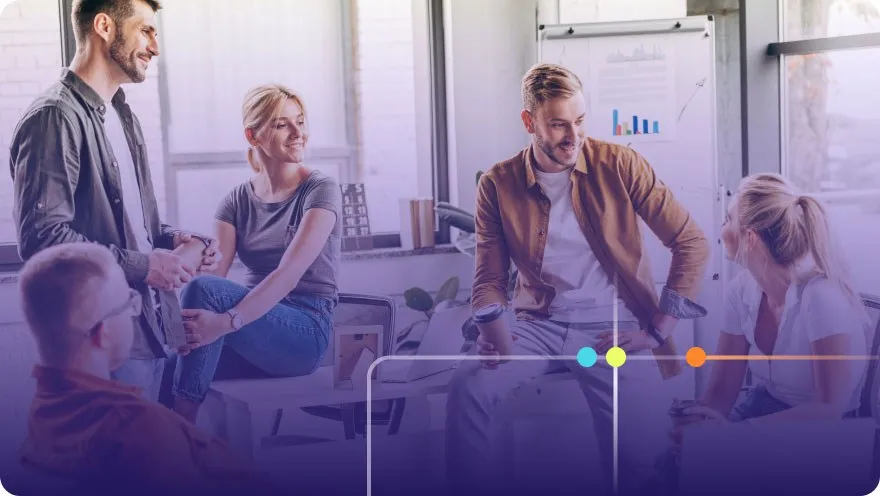 Group of coworkers having a casual conversation in a bright office with whiteboards behind them