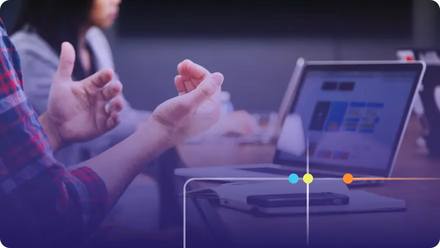 Person gesturing during a discussion with a laptop open on the table