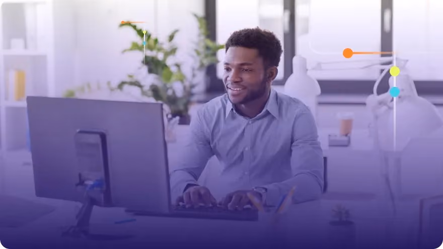Smiling man working at a desktop computer in a bright modern office