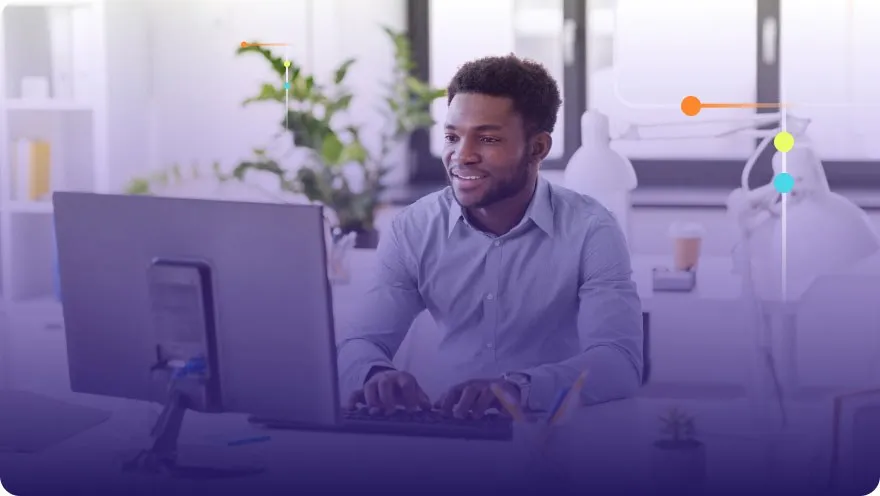 Smiling man working at a desktop computer in a bright modern office