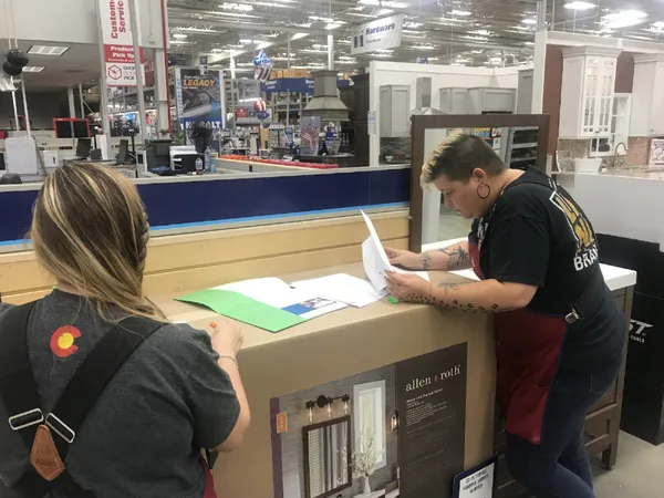 Customer and employee reviewing product paperwork at a hardware store service counter