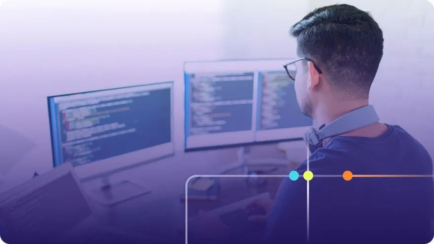 Developer with glasses working at a multi-monitor setup displaying code with purple overlay