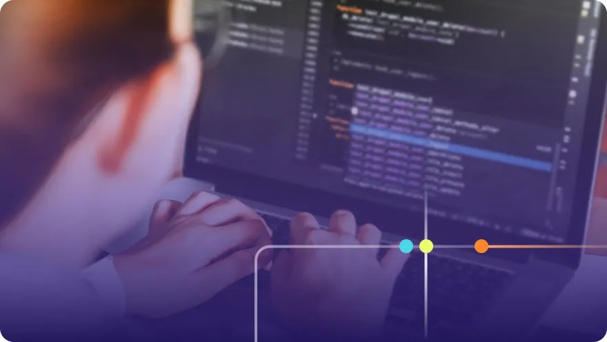 Developer typing on a laptop with colorful code displayed on a dark screen