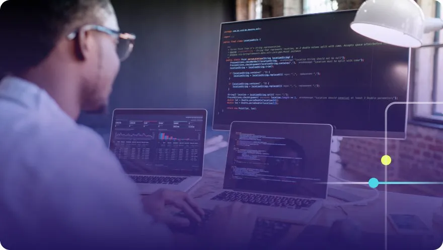Developer working at a multi-monitor setup with code and analytics dashboards on screen