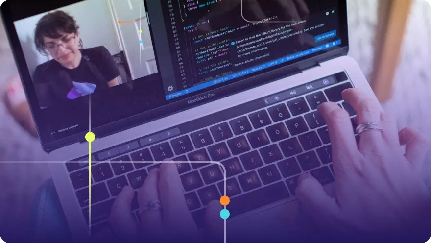 Developer pair programming on a MacBook Pro with code on screen and a video call visible