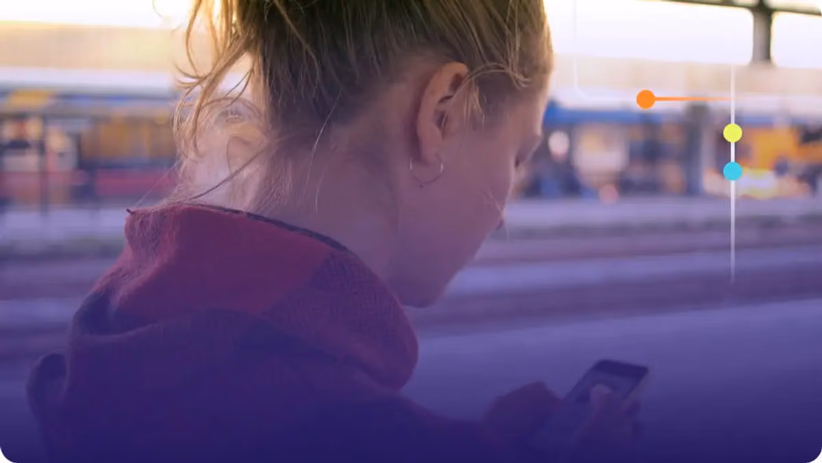 Woman looking down at her smartphone outdoors with a blurred urban background
