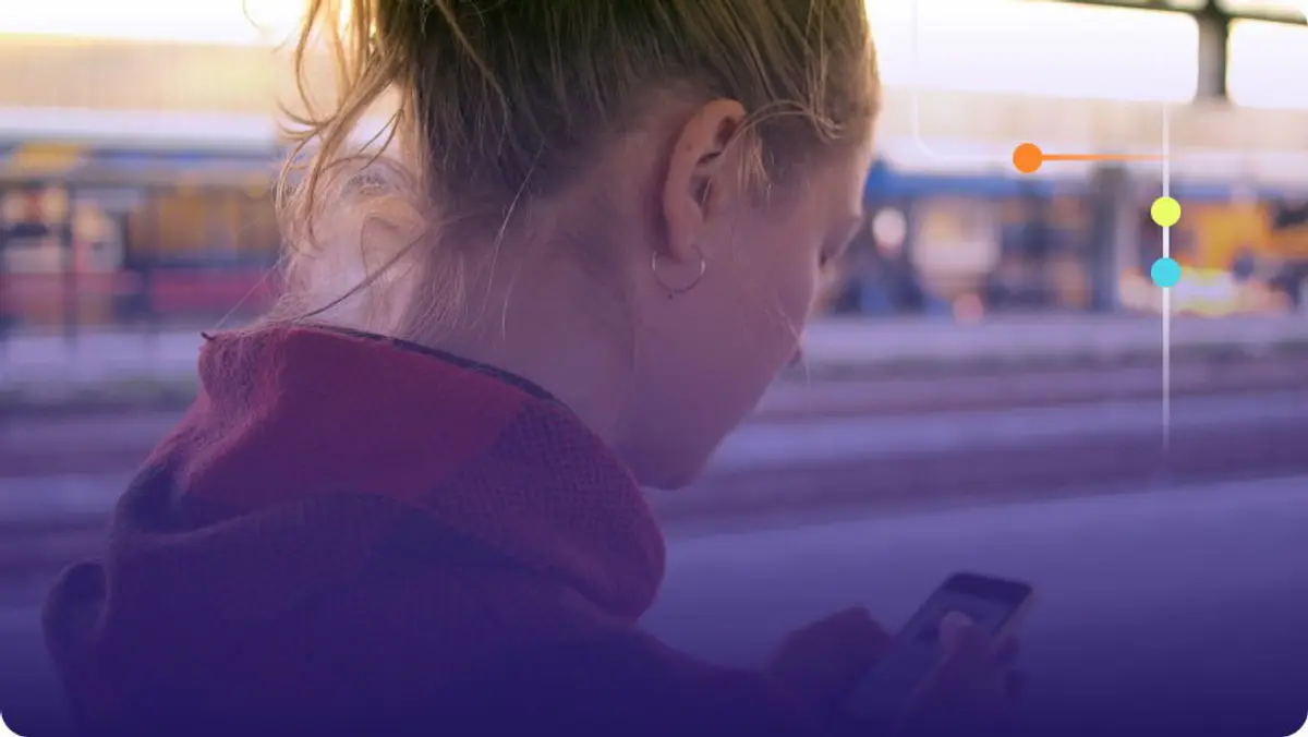 Woman looking down at her smartphone outdoors with a blurred urban background