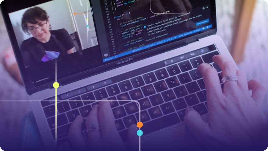Developer pair programming on a MacBook Pro with code on screen and a video call visible