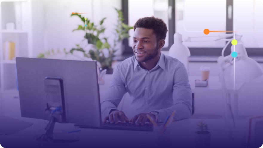 Smiling man working at a desktop computer in a bright modern office