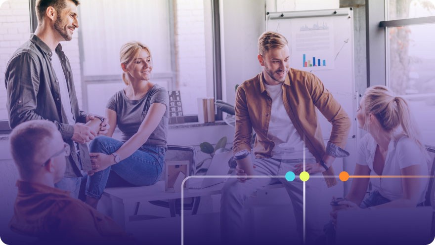 Group of coworkers having a casual conversation in a bright office with whiteboards behind them