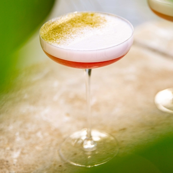 Cocktail clair à la mousse délicate servi dans un verre coupe