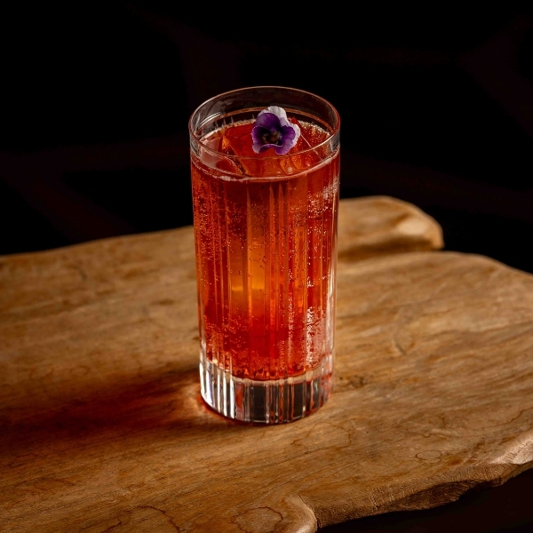 Boisson rouge aux reflets cuivrés servie sur table en bois