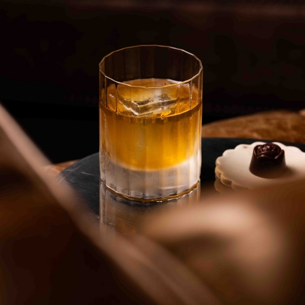 Cocktail signature aux nuances dorées servi dans un tumbler