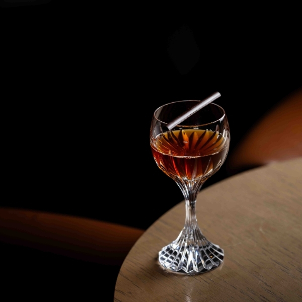 Cocktail sombre présenté dans un verre vintage sur fond noir