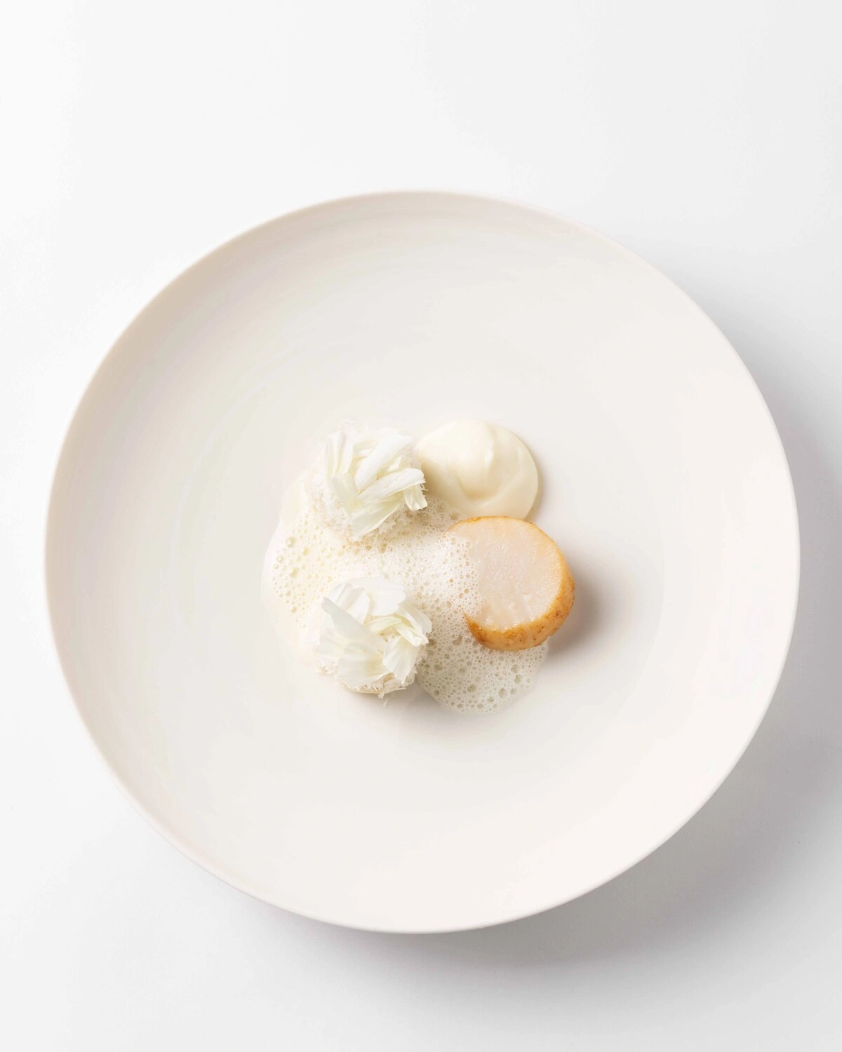Assiette minimaliste aux nuances de blanc, l'expression de la finesse culinaire française à Dubai.