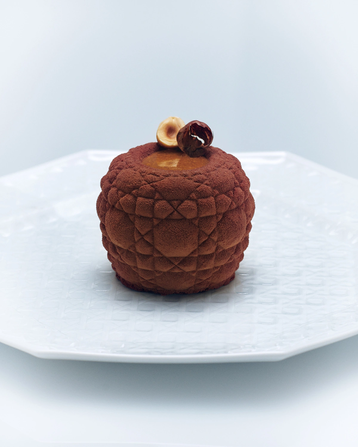 Dessert texturé aux reflets chocolatés, une œuvre artistique servie sur porcelaine Dior.