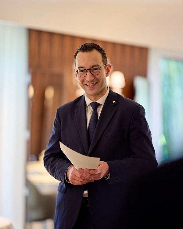 Homme en costume tenant un carnet au Restaurant Pic