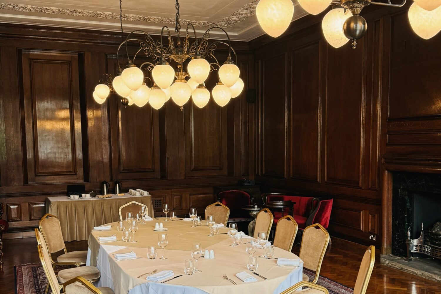 Oak-panelled Club Room at Manchester Hall with marble fireplace and ornate ceiling plasterwork