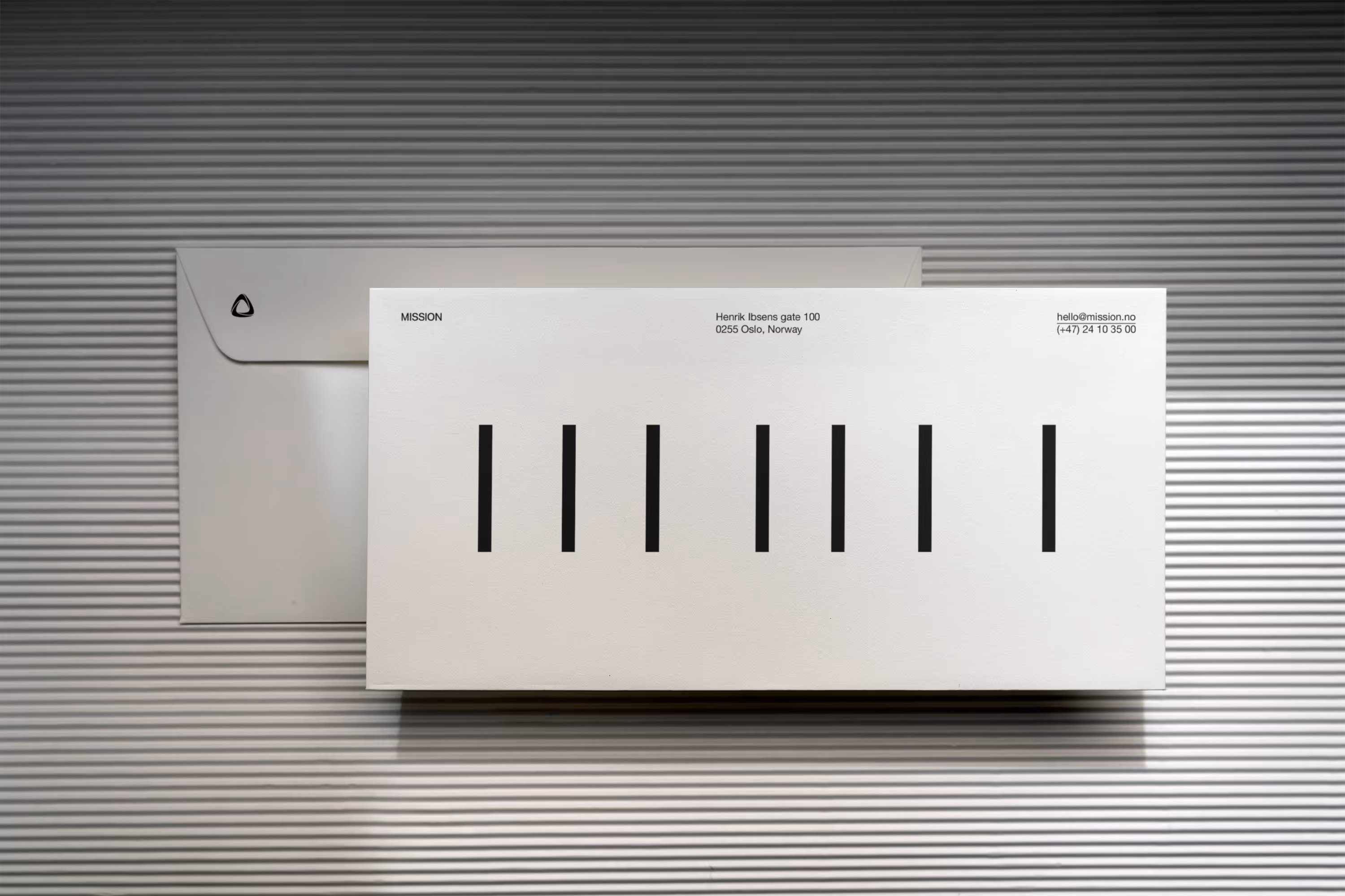 White envelope and letter with "MISSION" written with all characters rotated sideways so each character appears the same -  a black bar.