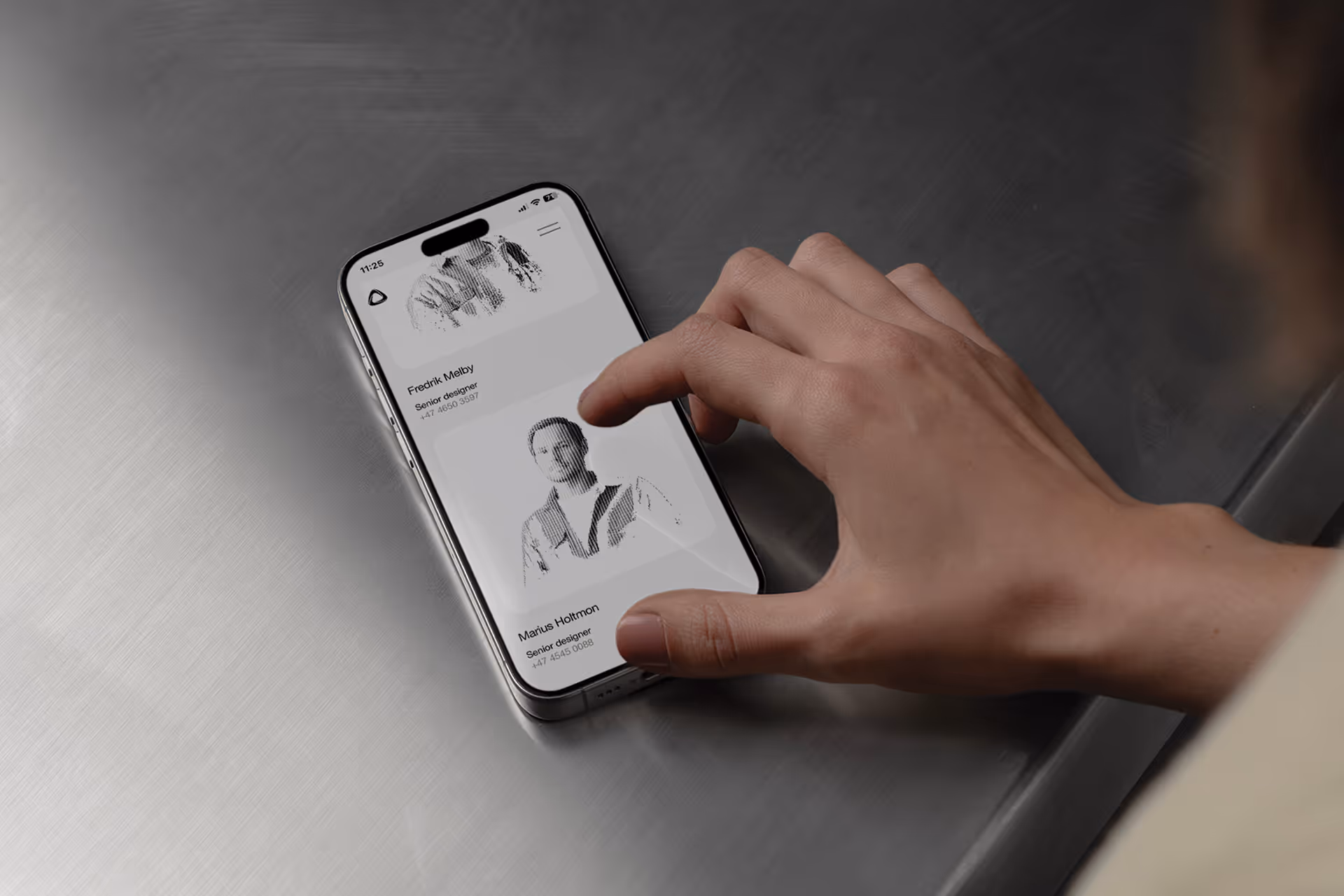 Hand holding a smartphone displaying a Mission website's contact section with pixelated profile pictures.
