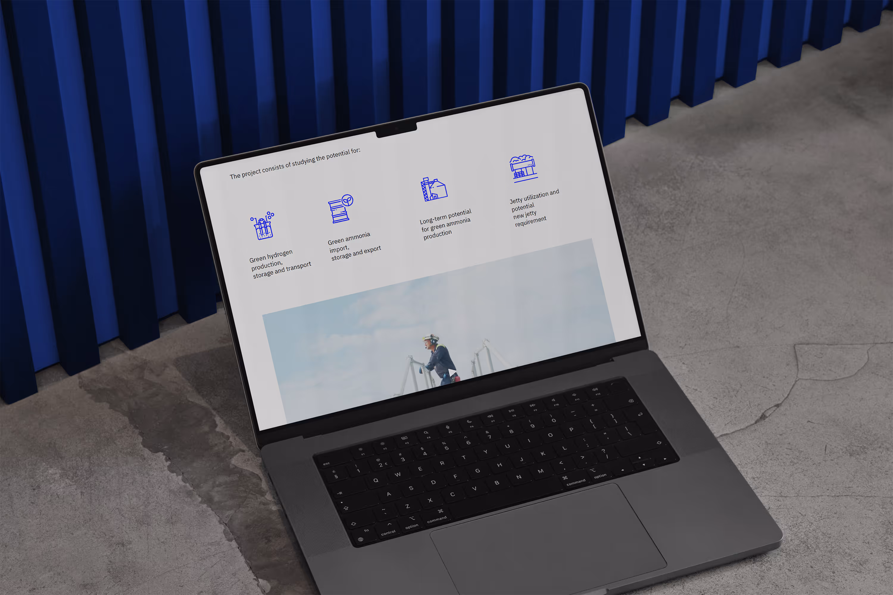 A laptop laying on the concrete floor showing a section from Slagen Energy Hub's website