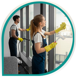 Zwei Mitarbeiter in Arbeitskleidung reinigen große Glasflächen in einem Geschäftsraum.