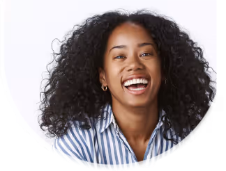 Smiling woman with curly hair wearing a blue and white striped shirt against a white background.