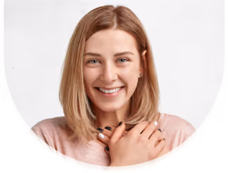 Smiling young woman with blonde hair and hands crossed over chest against a white background.
