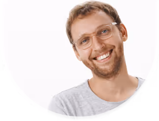 Smiling man with glasses and short hair wearing a gray t-shirt against a white background.