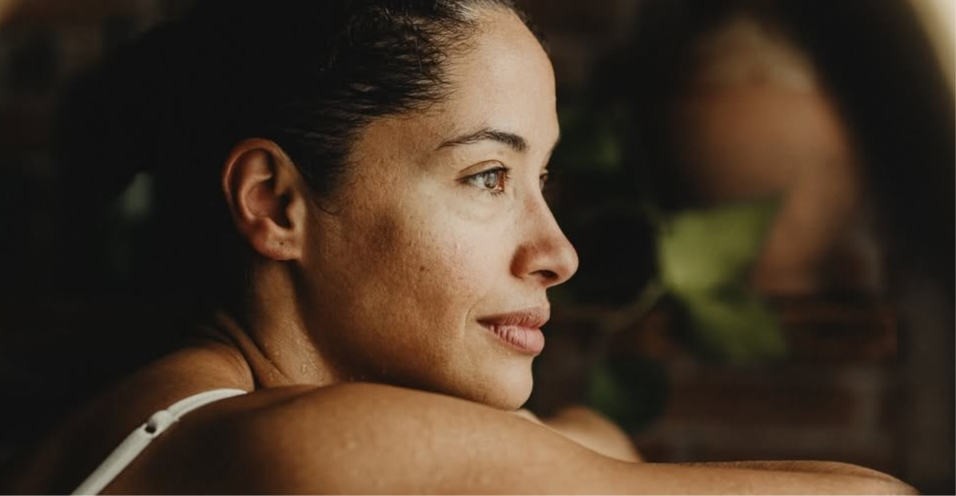 Close-up profile of a woman with damp skin leaning on her arms, looking slightly to the right.