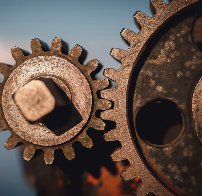 Close-up of two interlocking rusty metal gears with a blurred background.