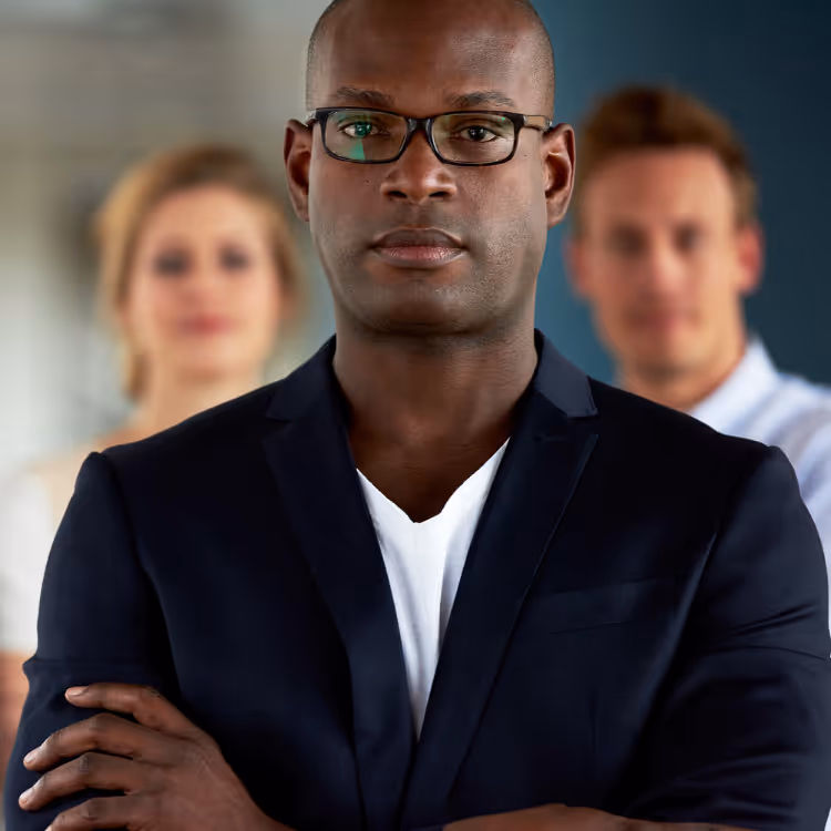 Person holding a small globe with green moss continents pointing at it with a pen, with environmental recycling charts and models on a table in the background.