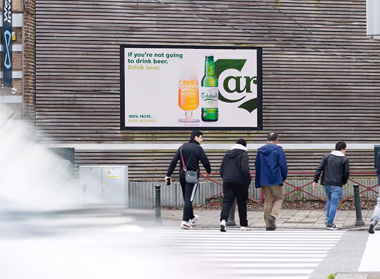 4 men walk past a billboard