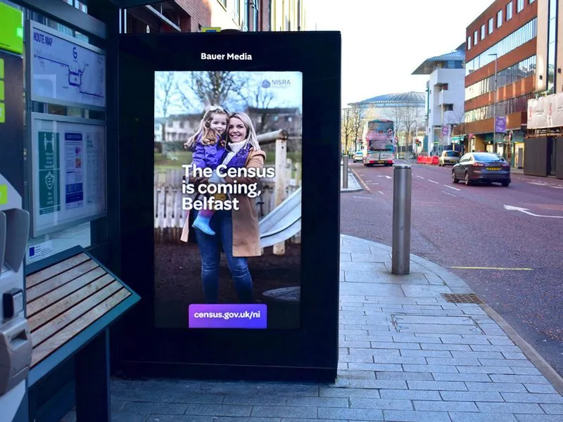 A bus shelter with a digital poster.