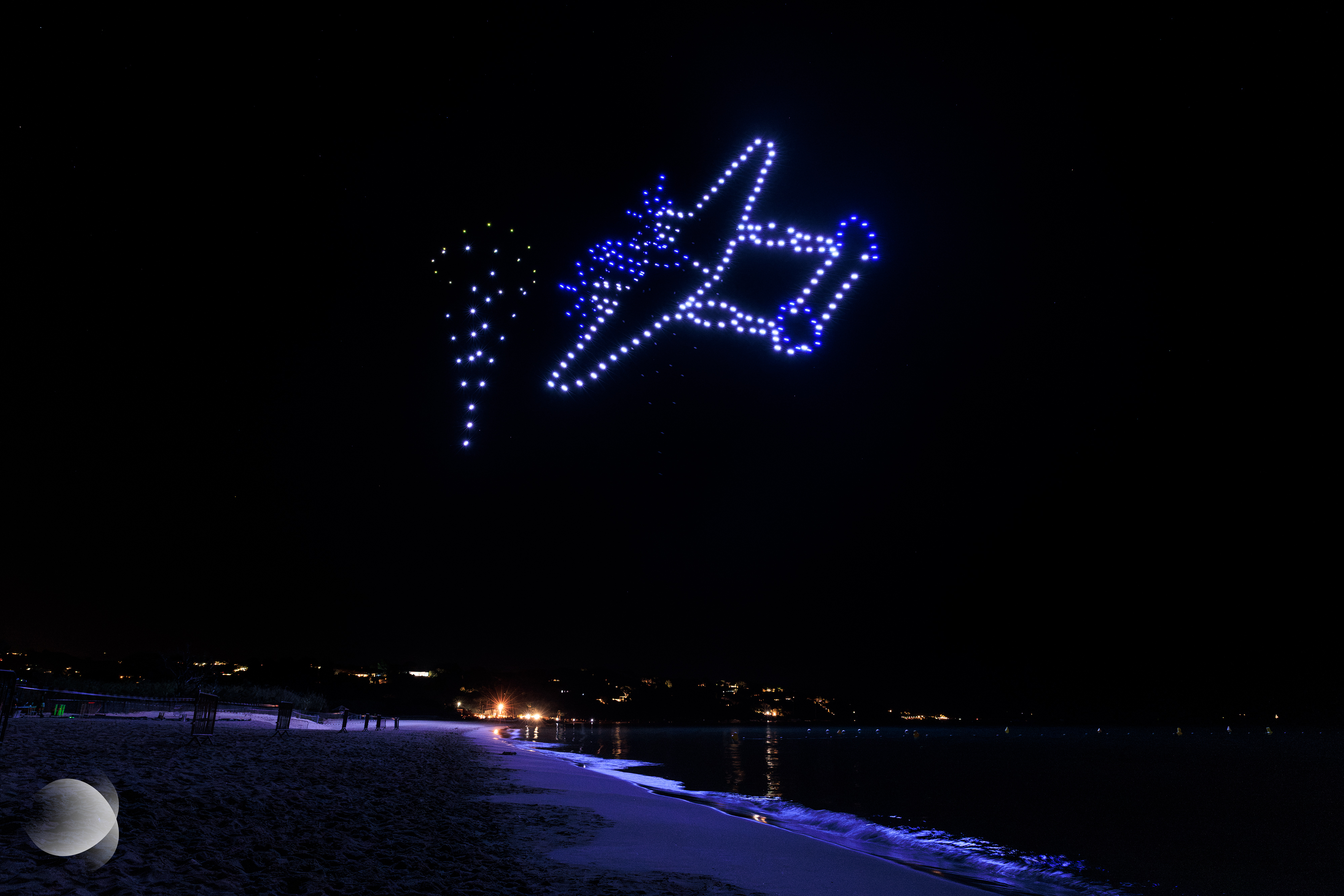 Drones formant un avion de reconnaissance P-38G Lightning passant devant les drones formant les parachutistes lors du spectacle de drones pour le Département du Var à Cavalaire-sur-Mer