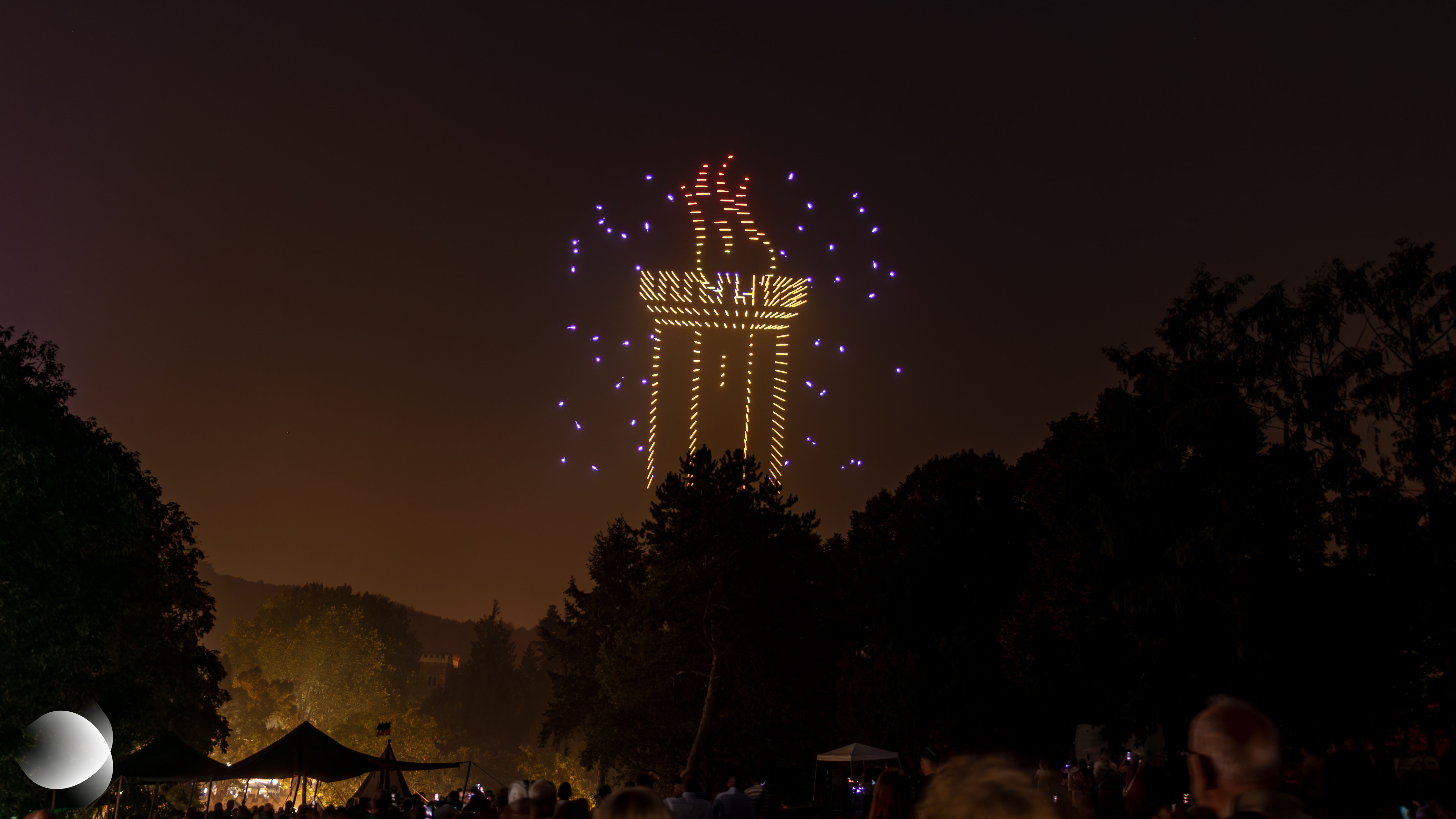 Représentation de la tour du Schlossberg de Forbach s’ouvrant progressivement dans le ciel nocturne grâce aux drones lumineux lors du spectacle « Johann Fischart, l’Humaniste », le 15 août 2026.