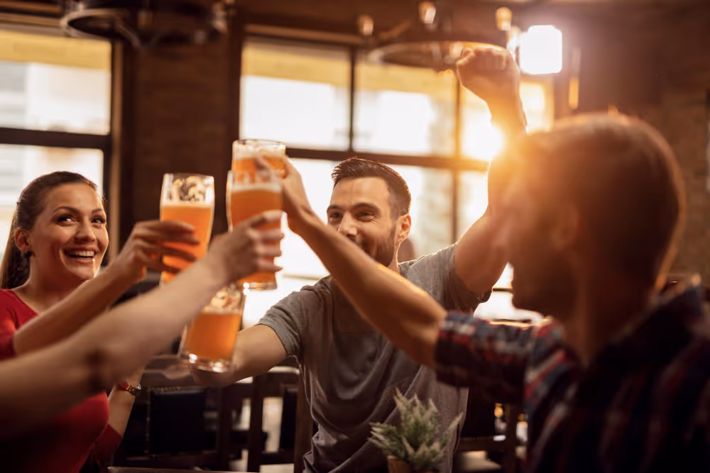 A man in a grey shirt is holding a glass of beer.