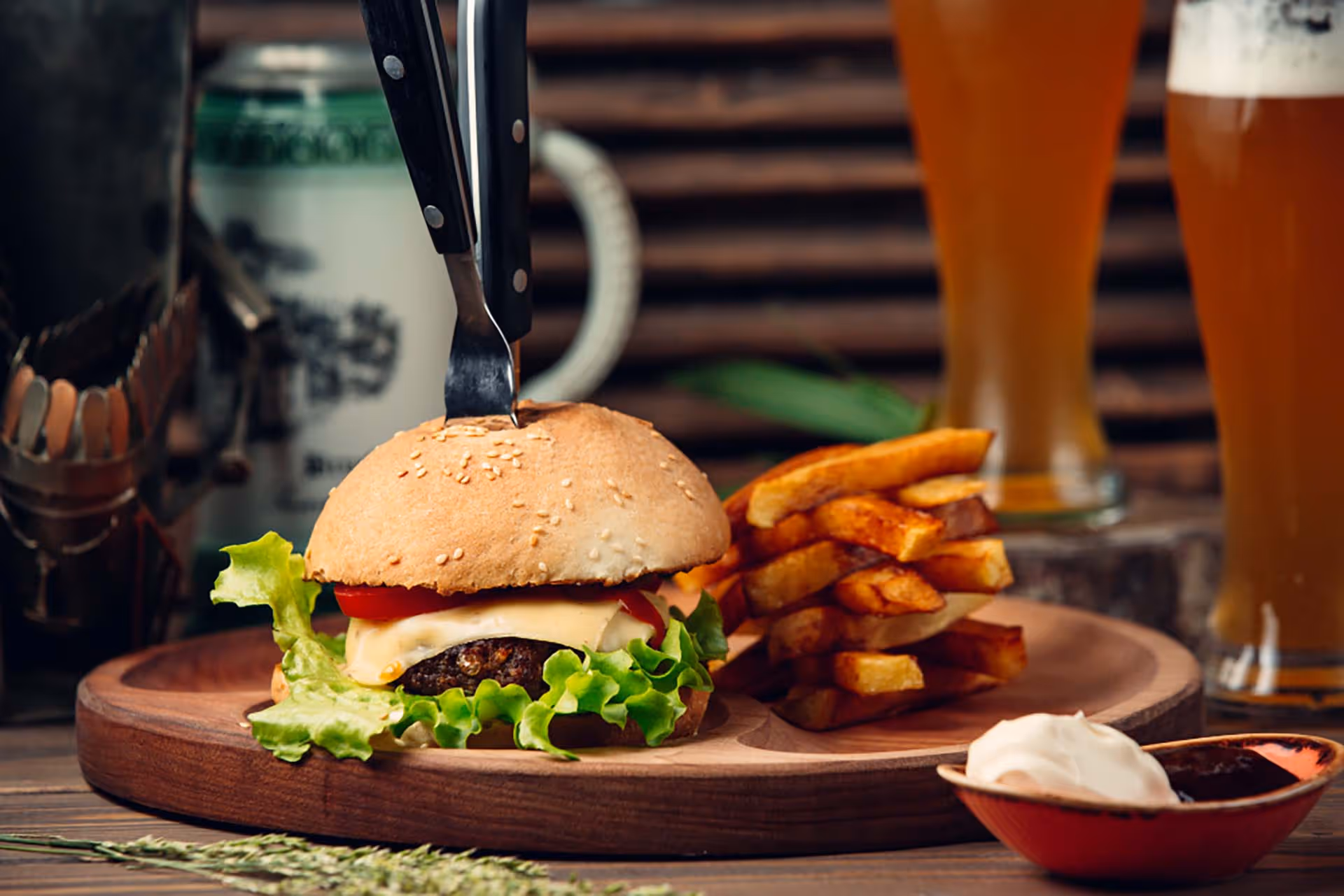 A burger with lettuce and tomato on a wooden cutting board.