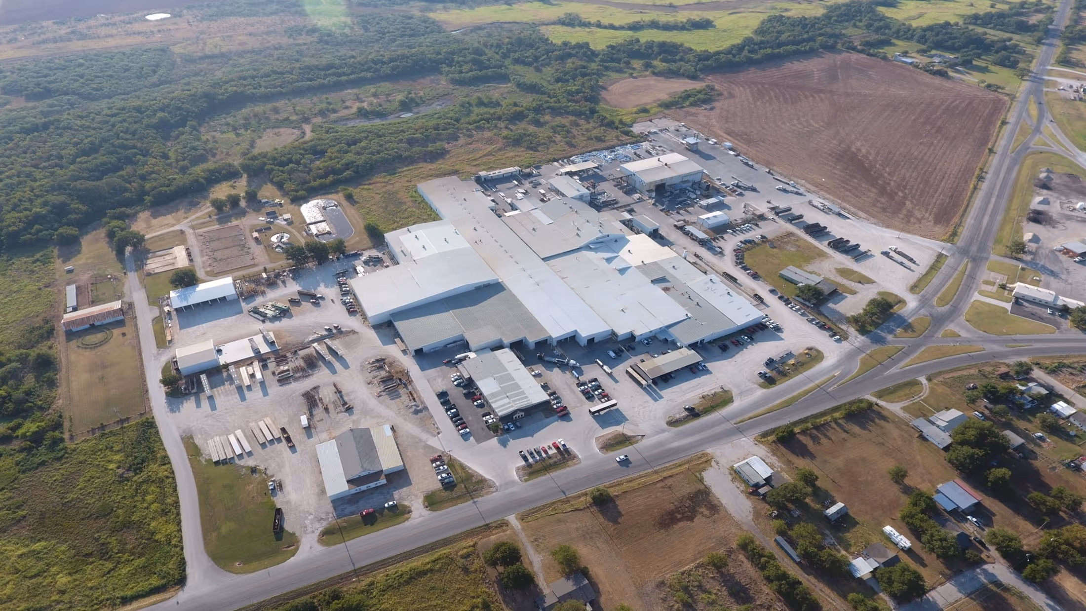 Aerial view of a large industrial warehouse complex surrounded by fields and roads.
