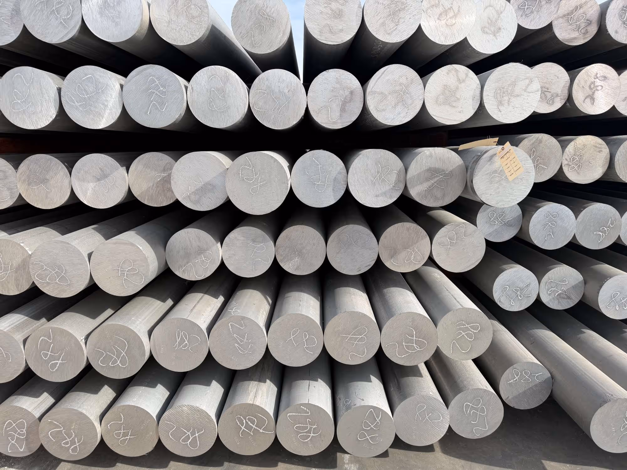 Stacked cylindrical metal rods with chalk markings on the ends.