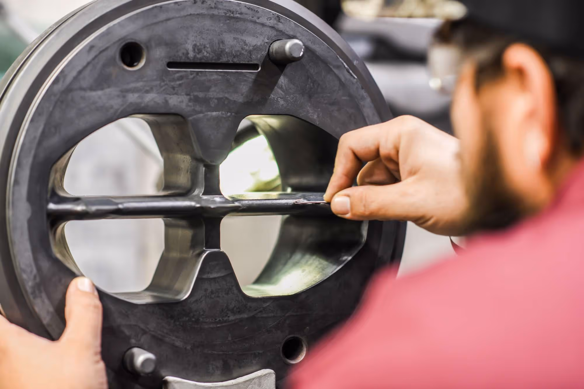 Technician inspecting the surface of a metal die used in manufacturing.