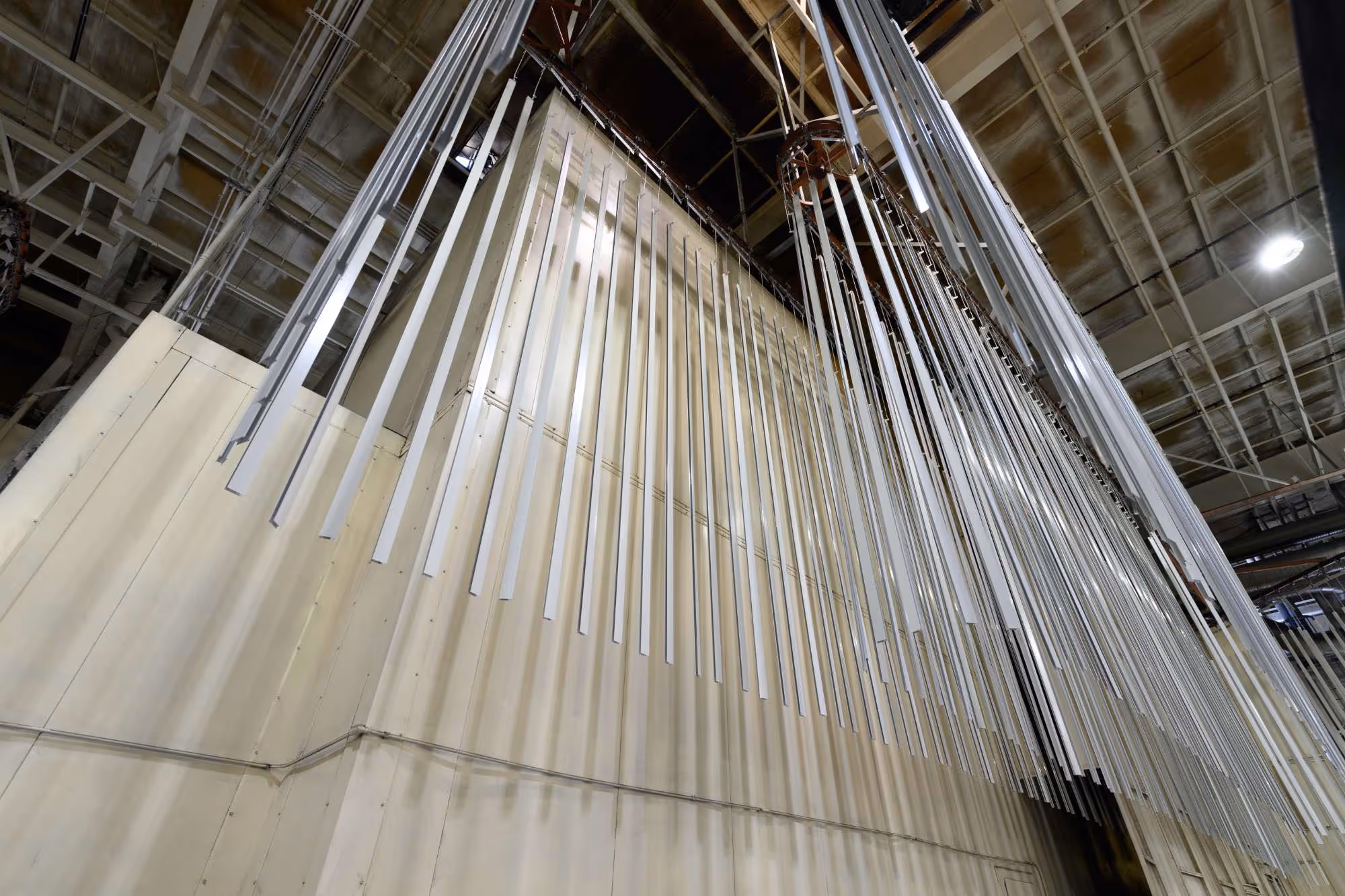 Long vertical metal pipes hanging from the ceiling in an industrial or theatre setting.