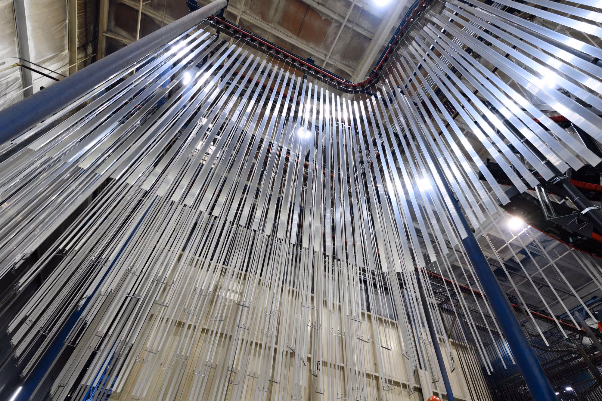Interior view of an industrial facility ceiling with numerous long vertical metal strips hanging down.