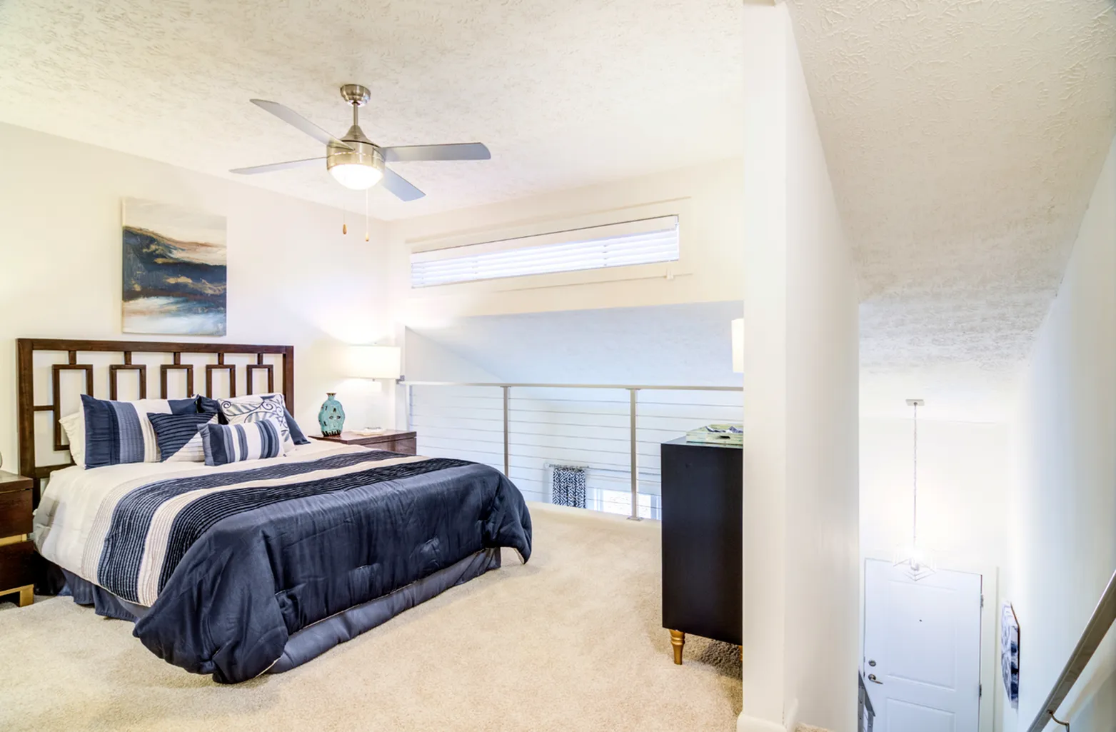 Furnished bedroom loft with staircase going down