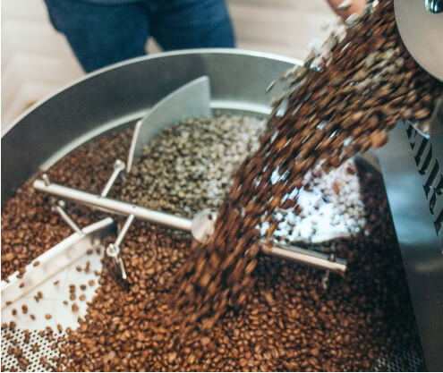 Coffee beans being poured into a processing machine.