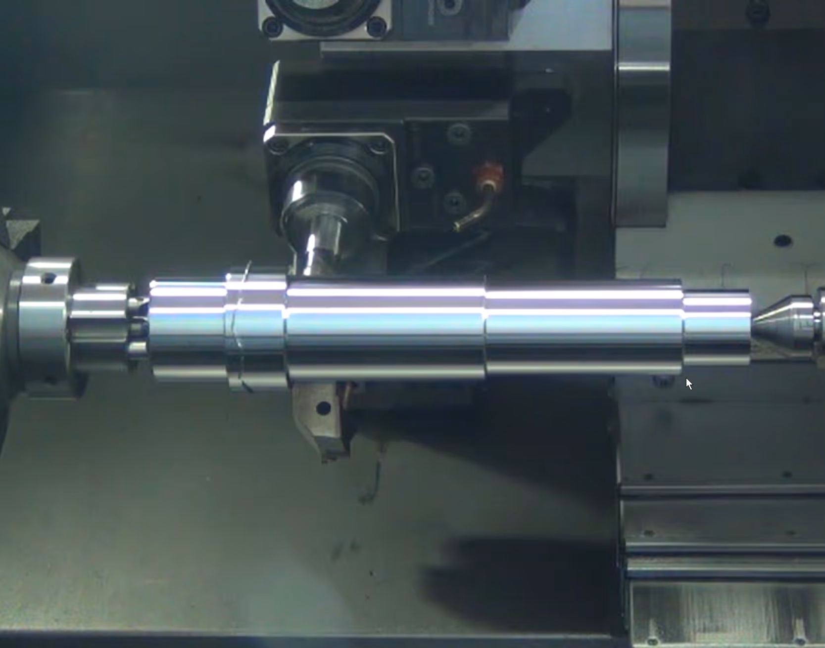 Close-up of a shiny metal cylindrical component being machined on a lathe.