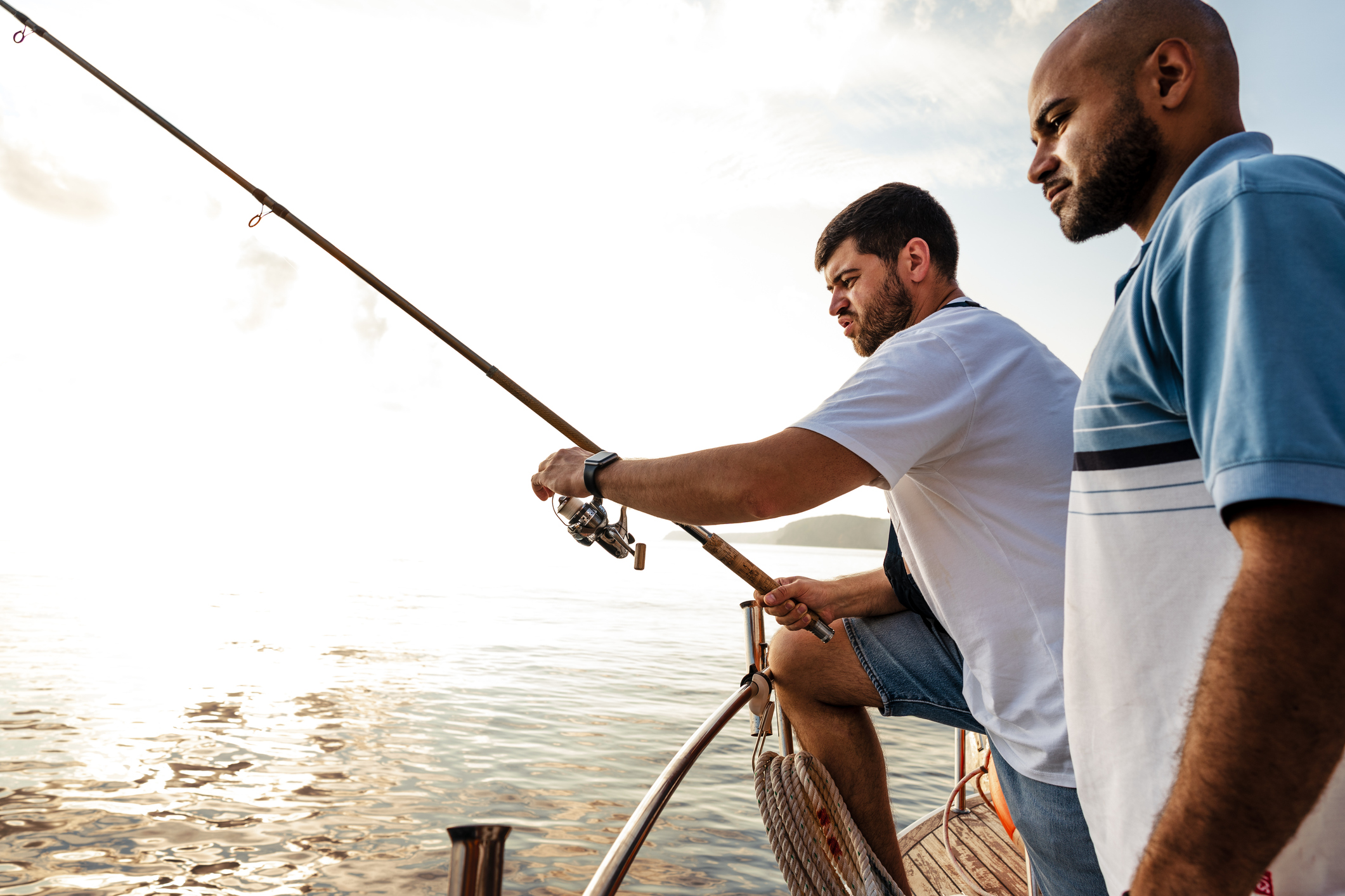 Two young men standing on charter boat with fishing rod, fishing together in Islamorada, FL.