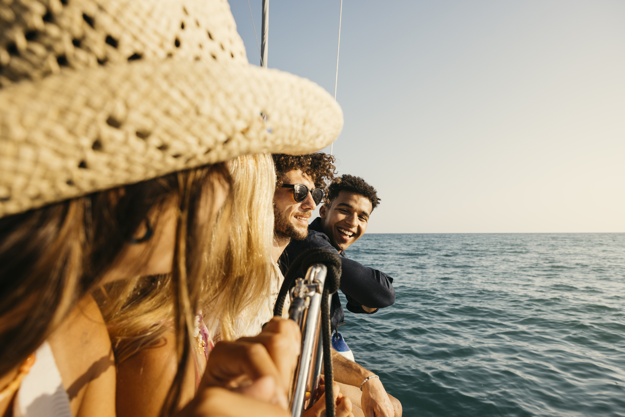 Group of friends enjoying a relaxing charter boat ride on the ocean. The sky is clear, and the waves are calm