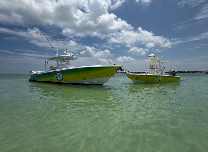 Two of A Fishing Guru’s fishing charter boats parked near Three Waters Marina in Islamorada, Florida. The water is a beautiful bluish-green hue and the sky is clear.